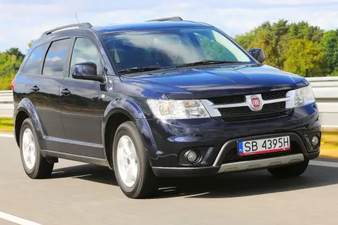 Ciemnoniebieski Fiat Freemont w ruchu drogowym. Wiele osób szuka fiat freemont opinie przed zakupem.