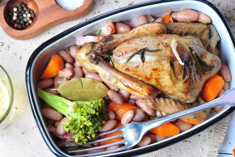 Ein köstlicher Braten von Tauben mit Bohnen, Karotten und Brokkoli, serviert in einer Auflaufform.
