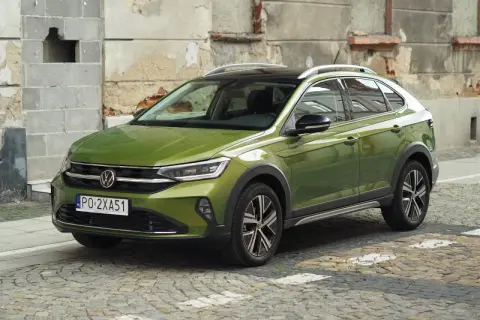 Zielony Volkswagen Taigo na brukowanej ulicy, z charakterystycznym dachem i felgami.
