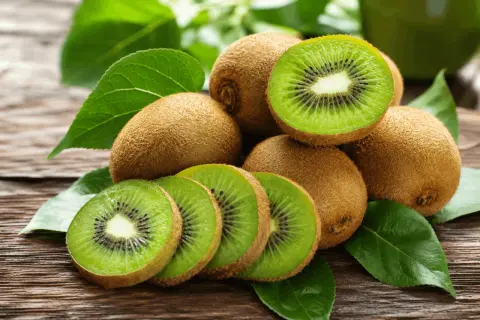 Kiwi frescos, cortados y enteros, sobre madera rústica. Una fuente natural de vitamina K para tu salud.