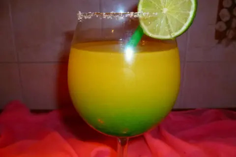 Orzeźwiający drink z Żabki, z zieloną słomką i plasterkiem limonki, ozdobiony cukrowym rantem.