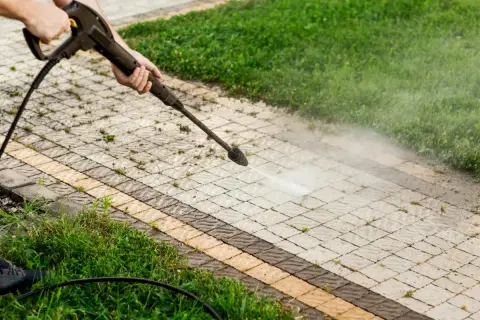 Pulizia del vialetto con idropulitrice per eliminare muschio con candeggina. L'acqua nebulizzata pulisce le fughe tra i blocchi di cemento.