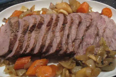Skivad kalvstek i ugn serverad med rotfrukter och lök. En härlig middag!