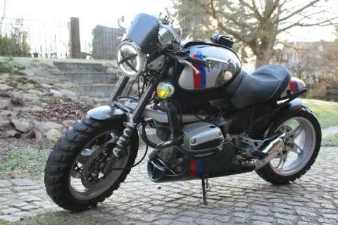 Zmodyfikowany BMW R 1100 R z okrągłym reflektorem i ozdobnymi pasami w barwach narodowych, gotowy na przygodę.