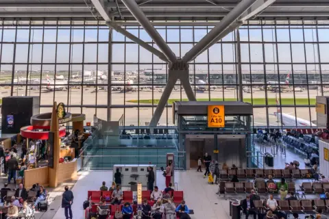 Wnętrze największego lotniska w Londynie, z widokiem na samoloty British Airways i pasażerów oczekujących na loty.