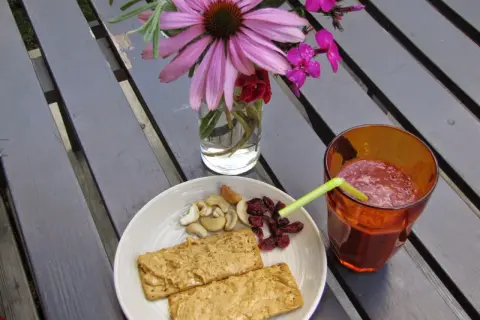 En tallrik med kex med jordnötssmör, nötter och torkade tranbär, samt ett glas smoothie. Perfekt för ett snabbt och gott mellis tips.
