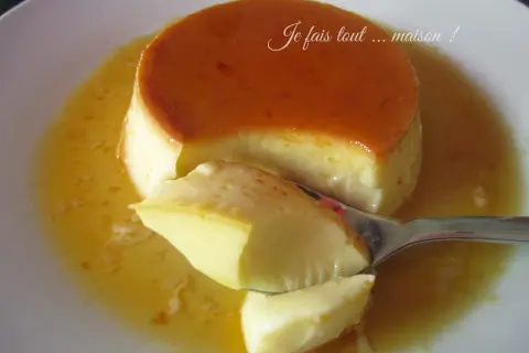 Une cuillère prélève un morceau d'un délicieux crème renversée maison, baignant dans son caramel doré.