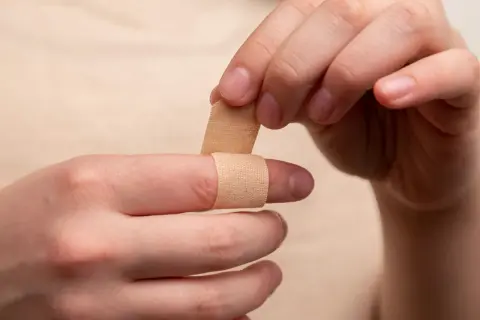 Dłoń zakłada plaster na palec. Czy ziarnina jest niebezpieczna? Pielęgnacja rany jest ważna.