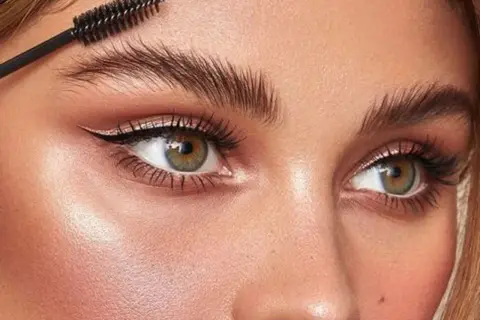 Cepillo peinando unas cejas perfectas para un laminado de cejas impecable.