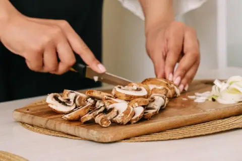 Krojenie pieczarek na desce. Czy pieczarki trzeba obierać? Zazwyczaj nie, wystarczy je oczyścić.