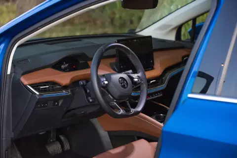 Eleganckie skoda enyaq wnetrze z brązową tapicerką, czarną kierownicą i dużym ekranem multimedialnym.