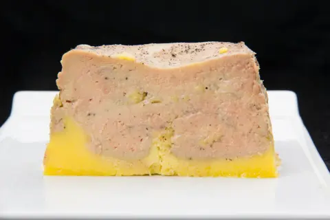 Tranche de pâté en croûte, avec une couche de viande rose et une base jaune, prête pour la cuisson.