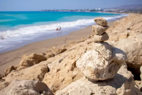 Kamienna wieża na skalistym brzegu, w tle turkusowe morze i piaszczyste plaże Pafos.