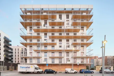 Edificio moderno con balcones de madera y metal. Posiblemente pisos de protección oficial en Barcelona, La Caixa, con vehículos aparcados.