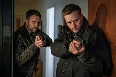 Två män med pistoler i händerna, redo för action i ett ny beck film.