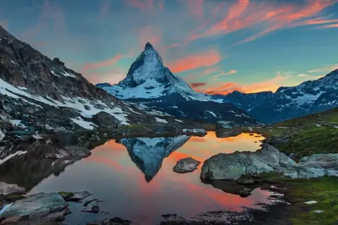 Zachód słońca nad jeziorem z odbiciem Matterhornu. Widok na wejście na Matterhorn, ośnieżone szczyty i malownicze niebo.