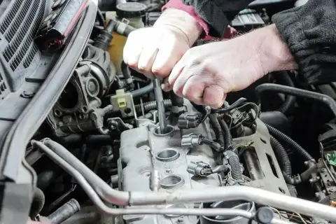 Mechanik wymienia świece zapłonowe w silniku. Pamiętaj o regularnej wymianie, by silnik pracował sprawnie.