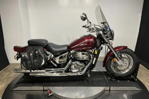 Motocicleta Suzuki Marauder 800 roja con alforjas de cuero y parabrisas.