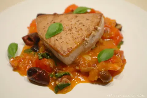 En saftig bit tonfisk serveras med en smakrik tomatsås, oliver och färsk basilika. Ett perfekt tonfisk recept för en härlig middag.
