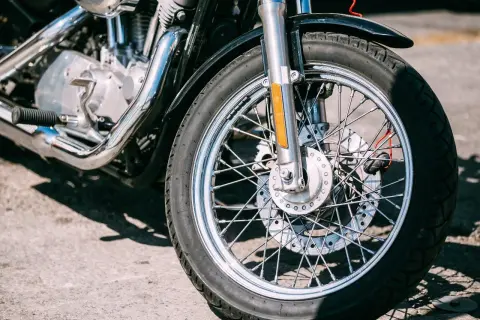 Zbliżenie na przednie koło motocykla z widocznym silnikiem i chromowanymi elementami.
