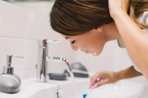 Kobieta płucze usta po umyciu zębów. Czy po umyciu zębów można jeść? Zależy od tego, co masz na myśli.