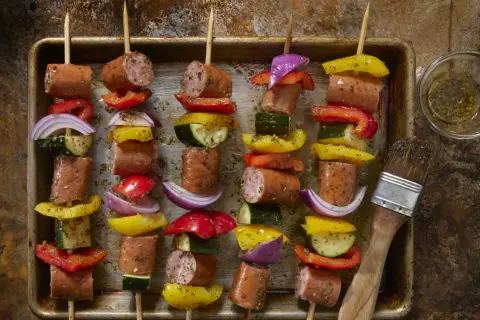 Spiedini di carne succulenti con peperoni, cipolle e zucchine, pronti per essere grigliati.