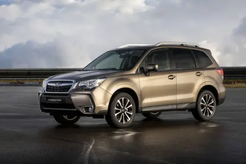 Subaru Forester color bronce, estacionado en asfalto mojado, con nubes en el cielo. A pesar de su apariencia, algunos **subaru forester problemas** son conocidos.