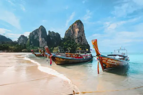 Bateaux traditionnels sur une plage de sable fin, parfaits pour organiser son voyage en Thaïlande et explorer les îles.
