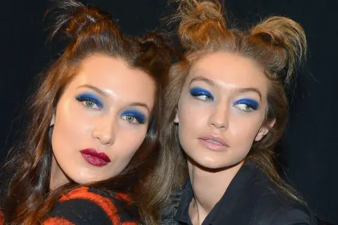 Due modelle con un'audace acconciatura semiraccolto e un vivace trucco occhi blu.
