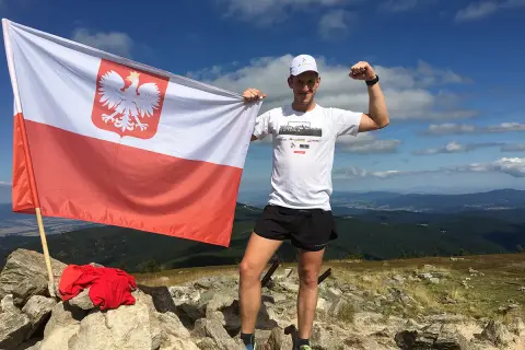 Zdobywca Korony Polskich Gór z biało-czerwoną flagą na szczycie.