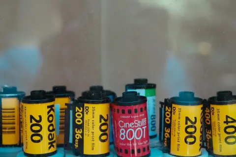 A collection of various types of 35mm film rolls, including Kodak 200, Kodak 400, and CineStill 800T, are displayed.