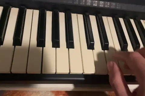 Dłoń gra akordy na keyboardzie, tworząc muzykę.
