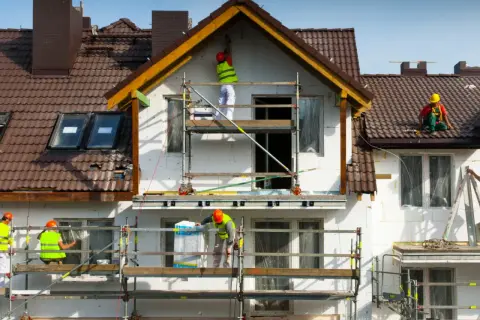 Pracownicy na rusztowaniach ocieplają dom. Może to być próba uniknięcia kary za samowolę budowlaną.