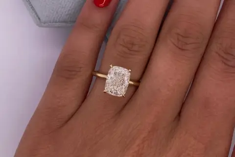 Olśniewający diament 3 karaty w prostym złotym pierścionku na dłoni z czerwonym lakierem do paznokci.