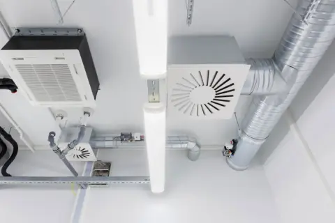 Sistema de ventilación mecánica para vivienda con conductos metálicos, unidades de aire acondicionado y luces LED en el techo.