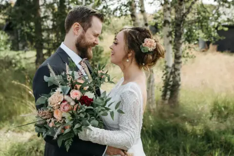 Un couple souriant, bouquet de mariage classique à la main. Idéal pour un texte remerciement mariage classique.
