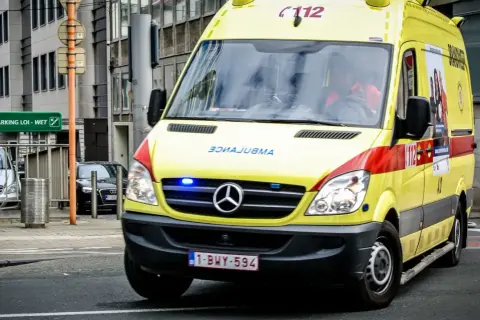 Ambulance jaune, véhicule prioritaire, roule en ville. Les gyrophares bleus clignotent.