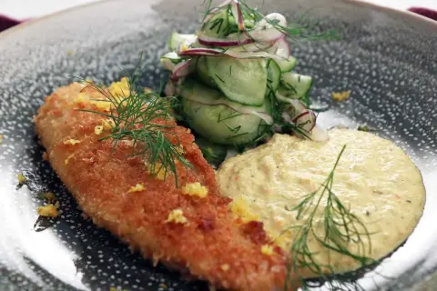 Panerad fisk med en krämig remouladsås curry, gurksallad och dill.