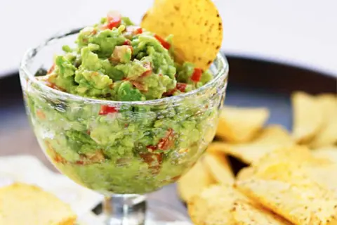 En skål med krämig guacamole, perfekt för ditt nästa guacamole recept. Serveras med tortillachips.