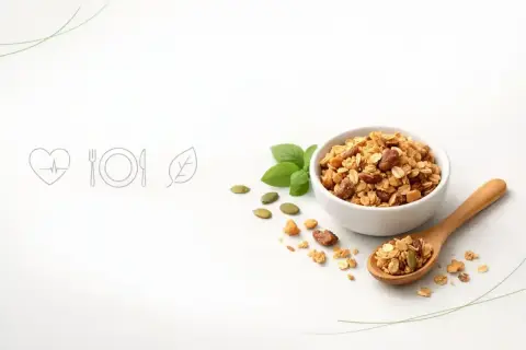 Chrupiąca granola w miseczce i na łyżce, obok pestki dyni i listki bazylii. To idealny pomysł na zdrowe śniadanie.