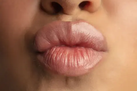 Labbra carnose e lucide, un primo piano che mostra come rimpolpare le labbra per un effetto voluminoso e sensuale.