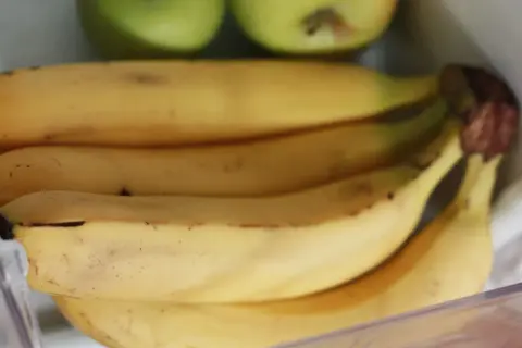 Pęk bananów w lodówce, obok zielonych jabłek. Czy banany można trzymać w lodówce? Tutaj są dowody.