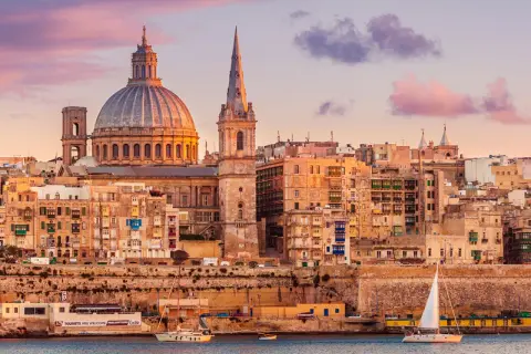 Sonnenuntergang über Valletta, Malta. Die Kuppel der St. Paul's Cathedral und Segelboote spiegeln sich im Wasser. Tolle Urlaub in Malta Erfahrungen!