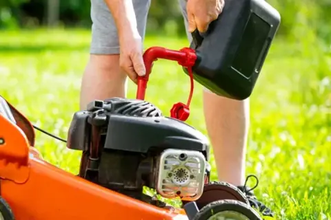 Mężczyzna nalewa paliwo do kosiarki. Zastanawiasz się, jakie paliwo do kosiarki będzie najlepsze?