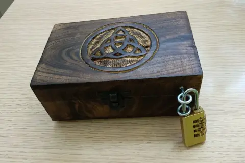 Caja de madera con símbolo celta y candado de combinación, lista para un escape room matematicas.