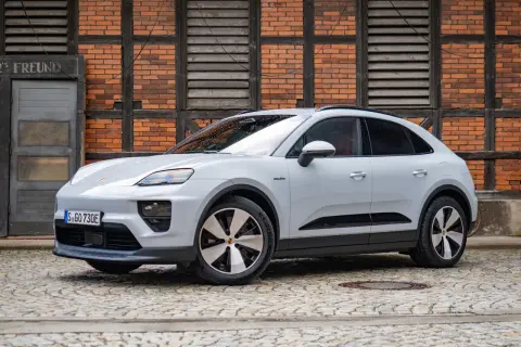 Biały Porsche Macan Electric na bruku, z ceglaną ścianą w tle. Sprawdź aktualną porsche macan cena.