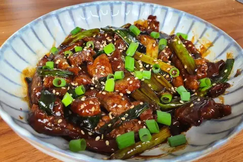 Un plat appétissant de boeuf aux oignons, garni de graines de sésame et d'oignons verts frais.