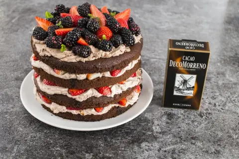 Obłędny tort czekoladowy z mascarpone i owocami: warstwy ciemnego ciasta przełożone kremem i świeżymi truskawkami, jeżynami i listkami mięty. Obok pudełko Cacao Decomorreno.