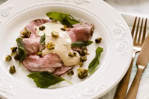 Skivor av tunt skuret kött toppas med en krämig tonfisksås, kapris och salviablad. En elegant portion av vitello tonnato.