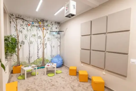 Przytulne studio z leśną tapetą, miękkimi pufami i panelami akustycznymi. Idealne miejsce do pracy nad dźwiękiem i tworzenia muzyki.